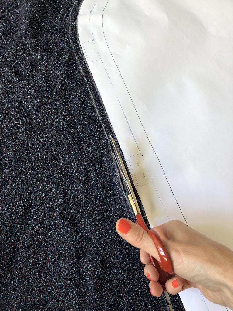 Hand mit Schere schneidet Stoffmuster